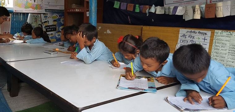 Young school children engrossed in study, sat at desks in a classroom in Nepal